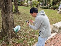 Estudiante escaneando el código QR de uno de los letreros en el área del Aljibe.
